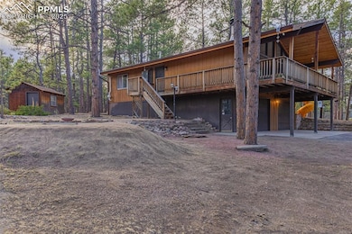 Rear view of property featuring driveway, an attached garage, stairway, and a deck