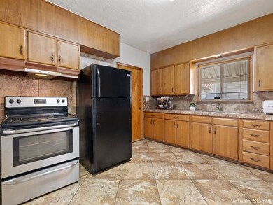 Kitchen featuring stainless steel electric range oven, decorative backsplash, freestanding refrigerator, light countertops, and a textured ceiling