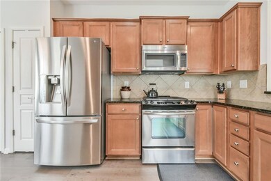 Kitchen featuring stainless steel appliances, dark stone countertops, and tasteful backsplash