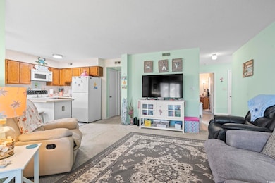 Living area featuring light carpet, a textured cei