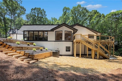 Back of property featuring stairway, a wooden deck, a sunroom, and roof with shingles