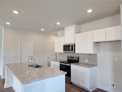 Kitchen featuring an island with sink, a sink, tas