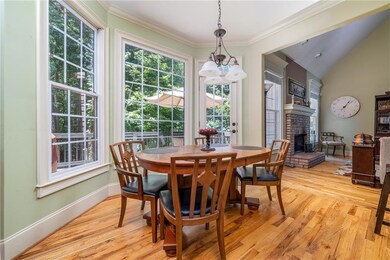 Dining space with a fireplace, light wood finished floors, a chandelier, crown molding, and lofted ceiling
