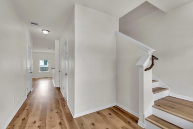 Hall with stairs, light wood-style floors, and ba