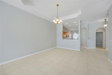 Unfurnished living room with a chandelier, arched walkways, recessed lighting, and baseboards