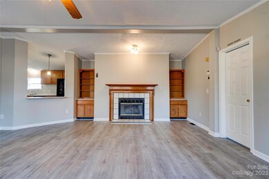 Living room with built in bookshelves, cabinets, and fireplace. Door on right leads to primary suite.