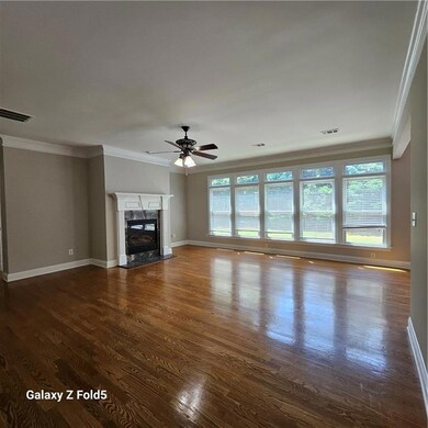 Unfurnished living room featuring dark wood-style floors, a ceiling fan, crown molding, and a premium fireplace