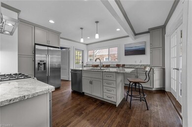 Kitchen with center island and bar seating, tile backsplash, stainless steel appliances and lots of cabinet storages.