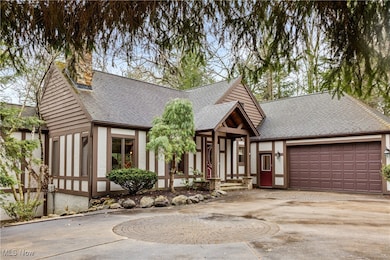 Tudor home with roof with shingles, driveway, an attached garage, and a chimney