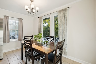 Dining room featuring ornamental molding, light tile patterned floors, and a chandelier