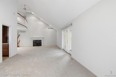 Unfurnished living room featuring a high end fireplace, high vaulted ceiling, light colored carpet, a ceiling fan, and recessed lighting
