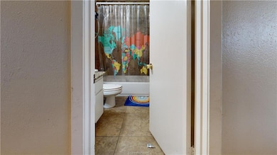 Bathroom with a textured wall, toilet, and tile pa