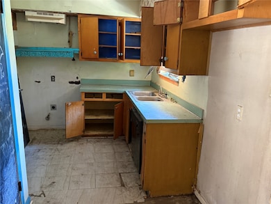 Kitchen with open shelves, brown cabinetry, light countertops, and light flooring