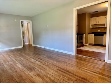 Unfurnished living room featuring wood finished floors and baseboards