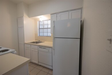 Kitchen with white appliances, a sink, light tile
