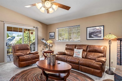 Carpeted living room featuring ceiling fan, vaulted ceiling, and a healthy amount of sunlight