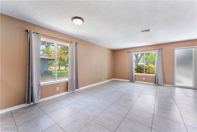 Empty room with light tile patterned floors, a tex
