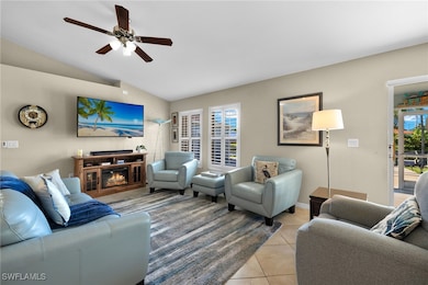Tiled living room featuring lofted ceiling, ceiling fan, and a healthy amount of sunlight