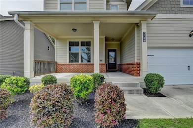 Doorway to property featuring a porch, brick siding, and a garage