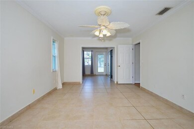 Spare room with crown molding, light tile patterned floors, ceiling fan, and baseboards