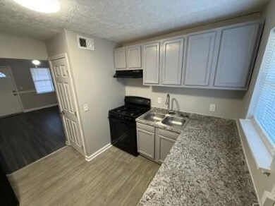 Kitchen featuring a sink, baseboards, under cabinet range hood, and black gas range oven