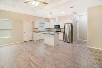 Kitchen featuring light hardwood / wood-style flooring, white cabinets, hanging light fixtures, and appliances with stainless steel finishes