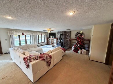 Carpeted living room featuring a wood stove, a textured ceiling, and a ceiling fan