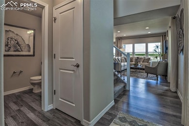 Corridor with dark wood-style flooring, baseboards, and stairs
