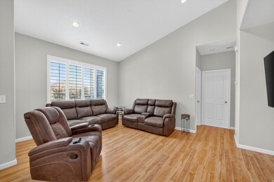 Living area with vaulted ceiling, recessed lighting, and light wood-style floors