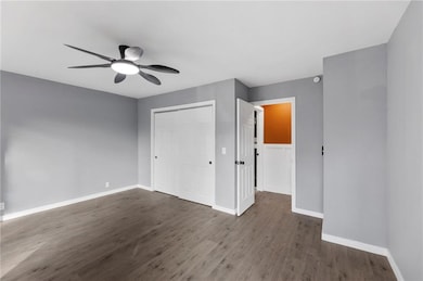 Main floor bedroom featuring wood finished floors, a closet, and ceiling fan