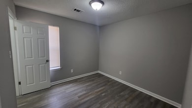 Unfurnished room featuring a textured ceiling and dark wood-style flooring