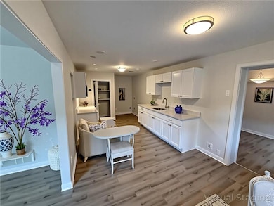 Kitchen with light wood-style flooring and white cabinetry