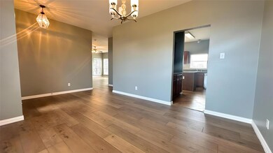 Spare room with baseboards, hardwood / wood-style flooring, and a chandelier