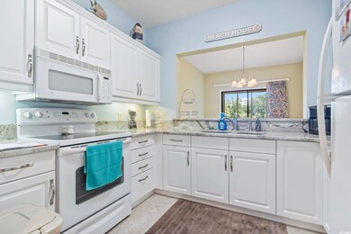 Kitchen featuring white appliances, a chandelier, white cabinets, decorative light fixtures, and light tile patterned floors