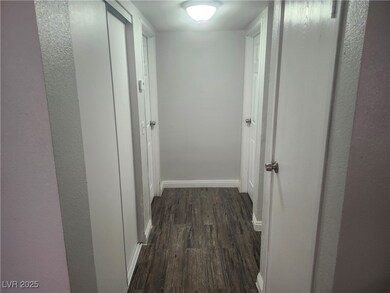 Hall featuring dark wood-style flooring and basebo