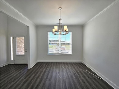 Unfurnished dining area featuring dark wood-style flooring, crown molding, and a chandelier