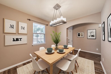 Dining room with arched walkways and dark wood finished floors