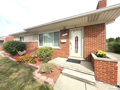 Entrance to property with covered porch, brick siding, and a lawn