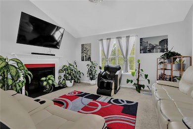 Carpeted living room with a fireplace with flush hearth and lofted ceiling