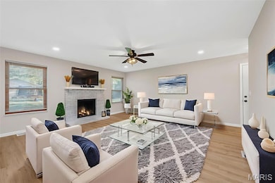 Living area with a ceiling fan, light wood-style floors, recessed lighting, and a brick fireplace