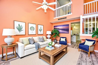 Living area featuring wood finished floors, baseboards, a towering ceiling, and a ceiling fan