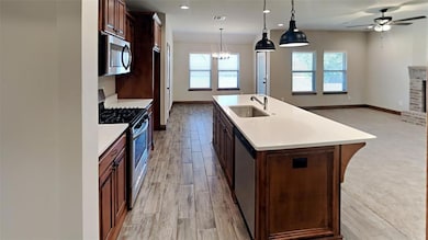 Kitchen featuring appliances with stainless steel finishes, light countertops, a ceiling fan, a center island with sink, and recessed lighting