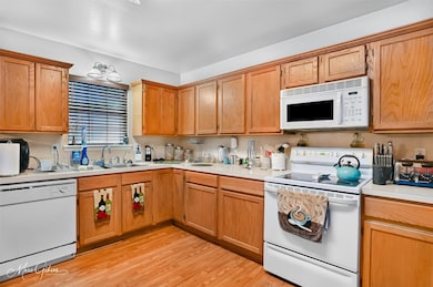 Kitchen with white appliances, light countertops, and light wood-style flooring