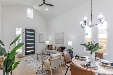 Living room with high vaulted ceiling, light wood finished floors, a chandelier, a ceiling fan, and recessed lighting
