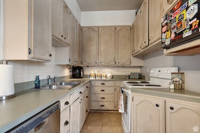 Kitchen featuring white electric stove, dishwasher, decorative backsplash, and light countertops