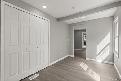 Unfurnished bedroom featuring recessed lighting, light wood-style floors, beamed ceiling, and a closet