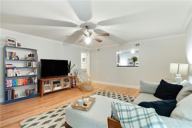 Living area featuring ceiling fan, crown molding, wood finished floors, and baseboards