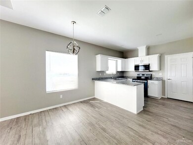 Kitchen with visible vents, stainless steel microwave, range with electric stovetop, a peninsula, and white cabinets