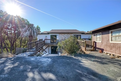 Rear view of house featuring a wooden deck, stone