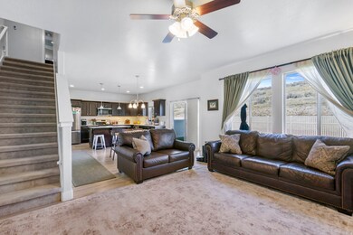 Living room with stairs, light wood-style flooring, a ceiling fan, and recessed lighting
